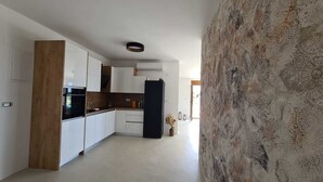 A modern kitchen with white cabinets, a black refrigerator, and a wooden accent piece. - Villa SOL Insulam (Novalja)