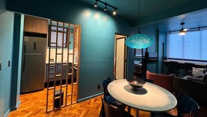 Una cocina moderna con refrigerador, una mesa de comedor con sillas y una pared azul.