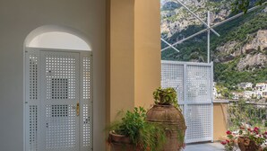 A balcony with terracotta pots and a view of a mountainous landscape. - Casa Bijou (Positano)