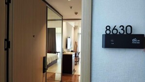 A hotel room with a bed, desk, and a wall-mounted sign displaying the number 8630. - Hequan Farm (Bengbu)