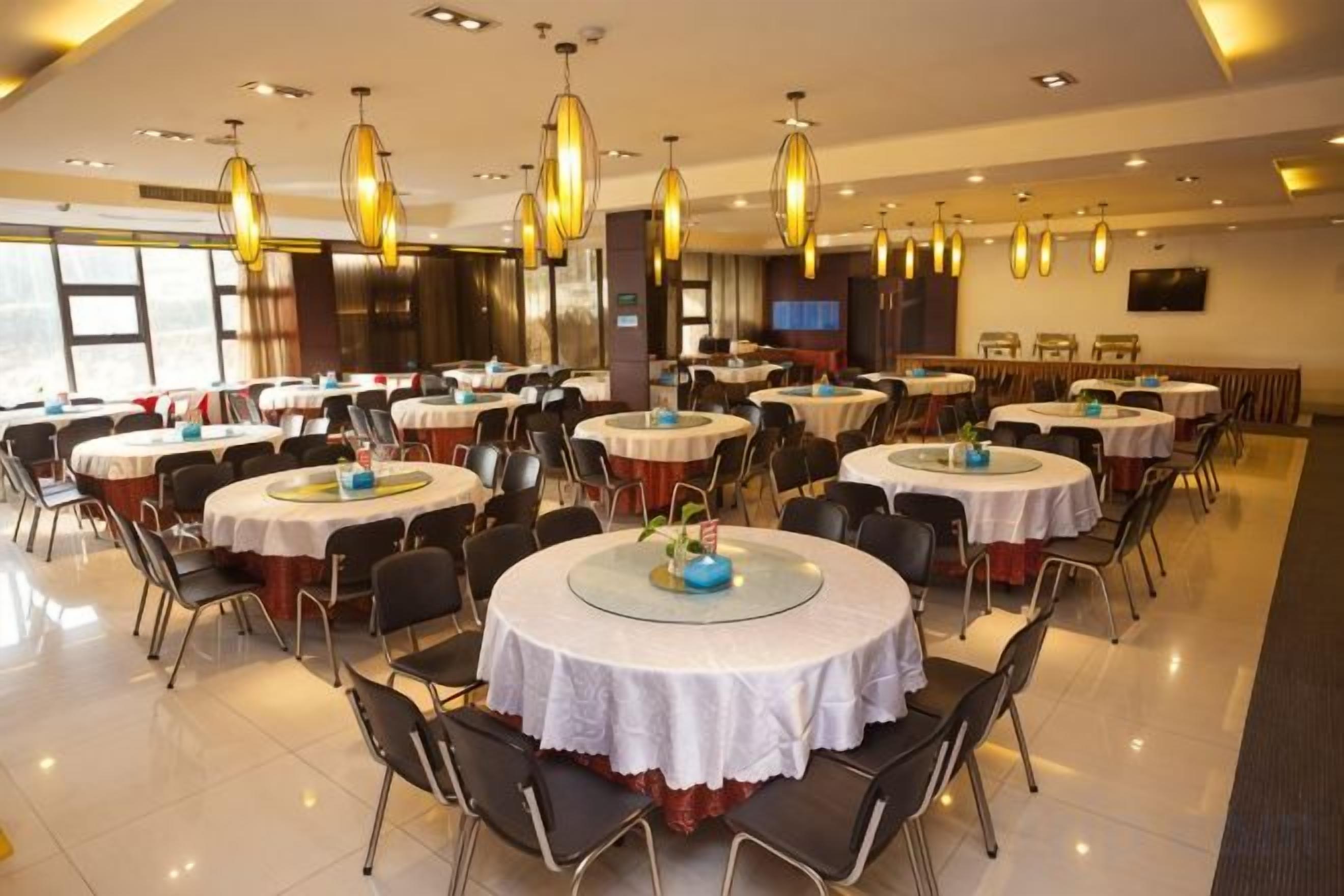 A dining area with round tables, chairs, and hanging light fixtures.