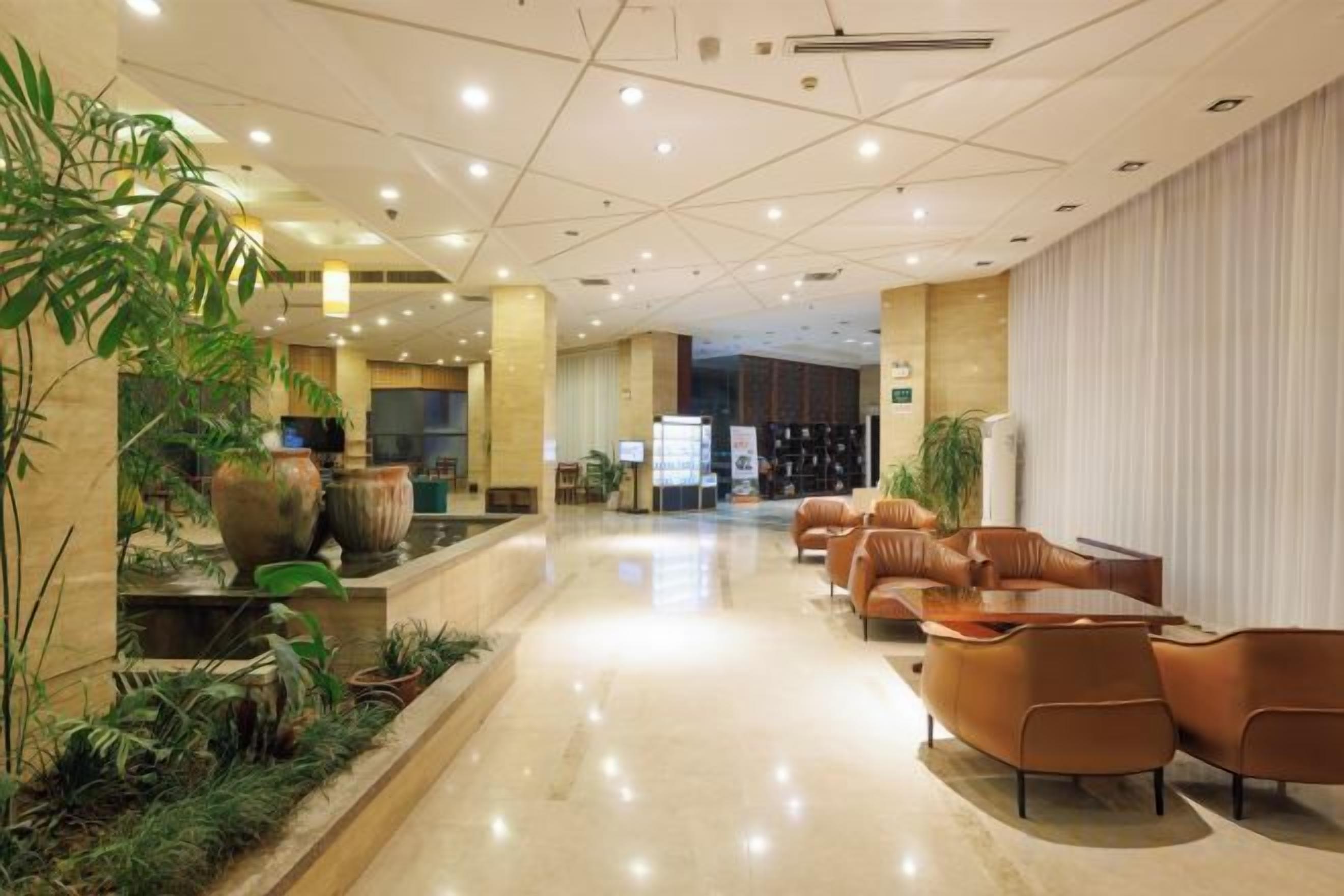 Un hall d’hôtel comprenant un comptoir d’accueil, un espace salon et des plantes d’intérieur.