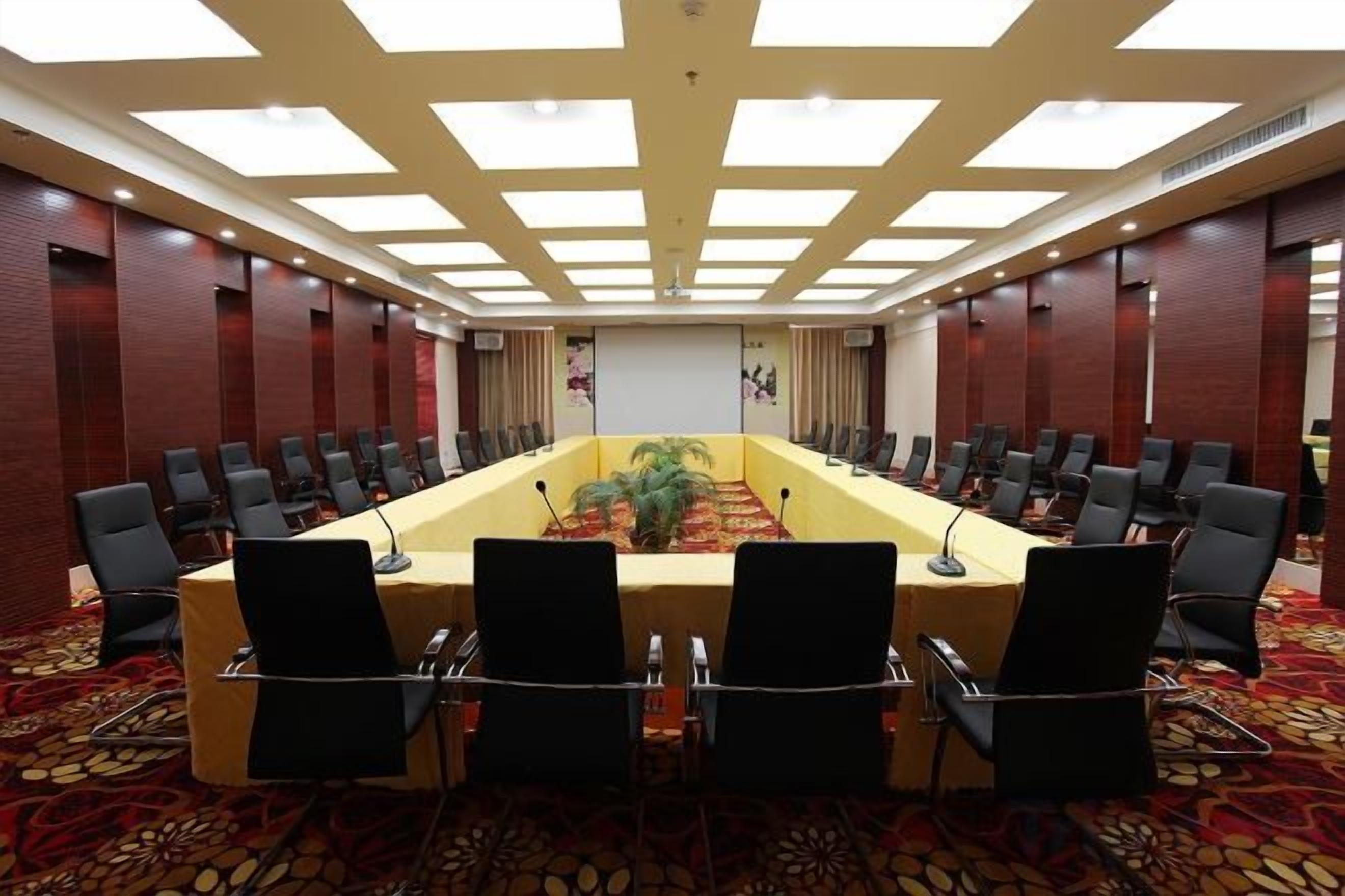 A conference room with a long table, multiple chairs, and a carpeted floor.