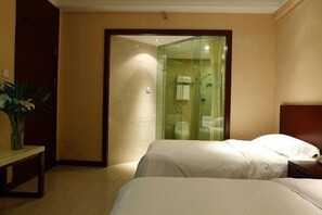 A hotel room with two beds, a glass-enclosed shower, and a wooden bench.