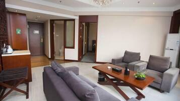 A modern hotel lobby with a reception desk, sofas, a wooden coffee table, and a chandelier.