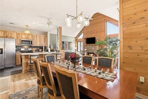 Eine geräumige Küche mit Holzausstattung, ein Essbereich mit Holztisch und -stühlen sowie ein großes Fenster für natürliches Licht.
