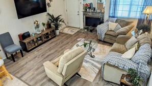 Una sala de estar con televisión de pantalla plana, chimenea y un conjunto de sofás.