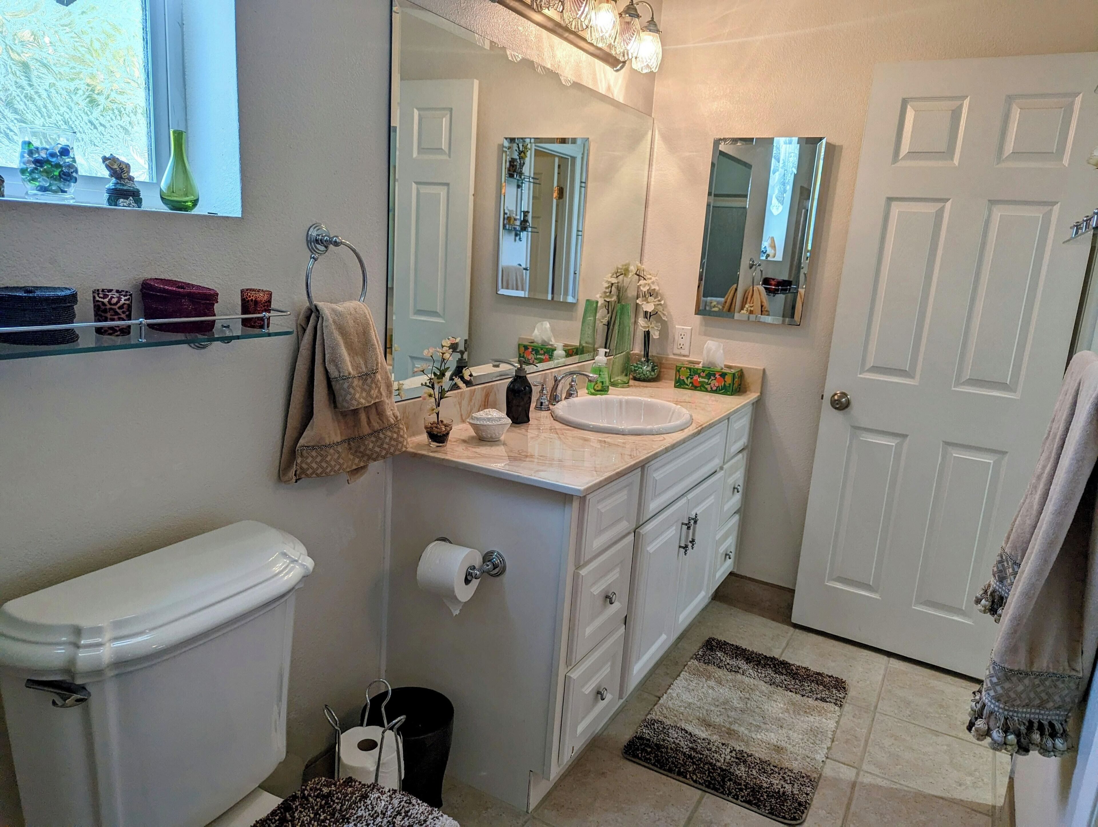 Une salle de bain équipée de toilettes, d’un lavabo, d’un miroir et d’un porte-serviettes.