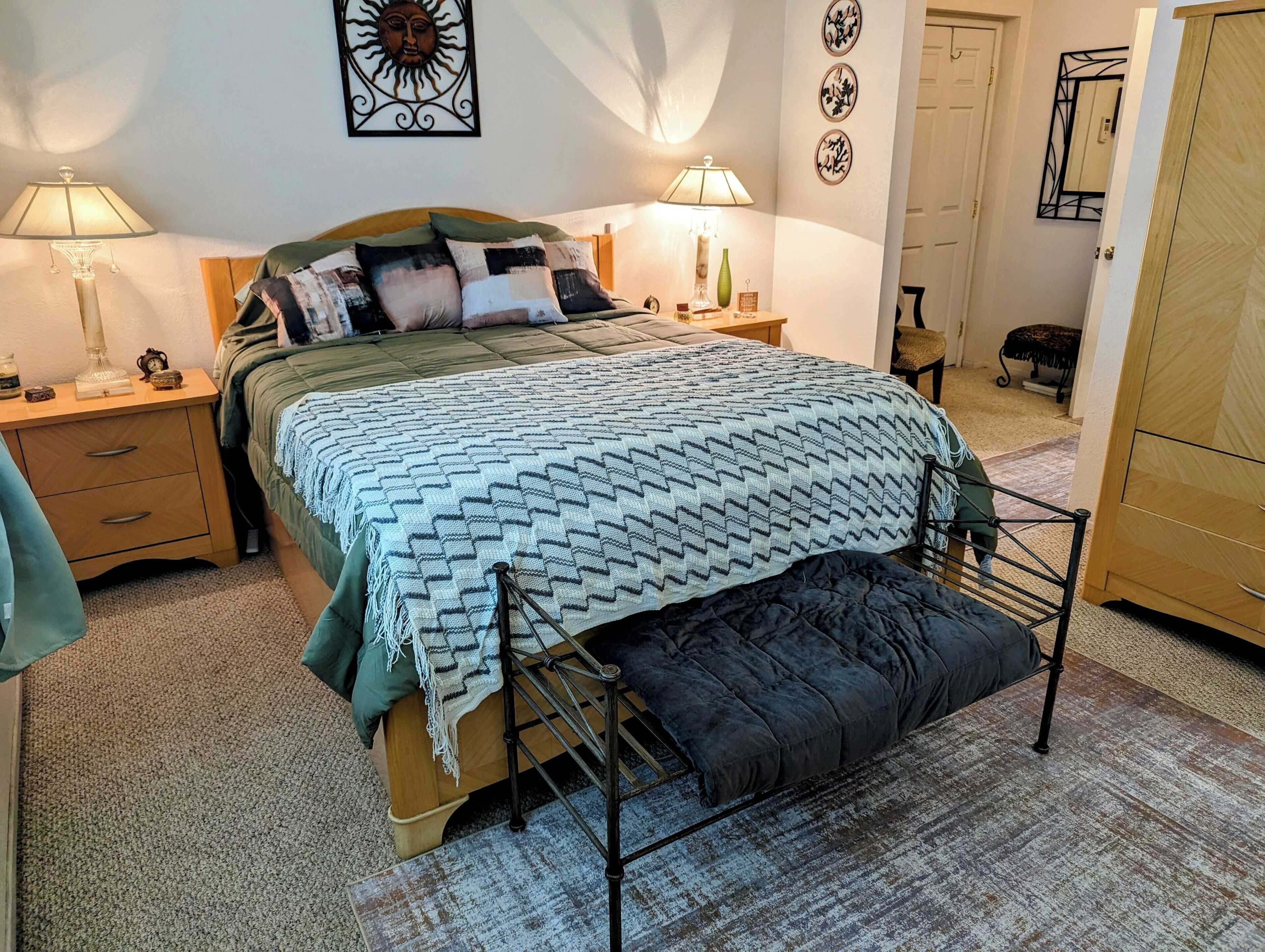 Una camera da letto con un letto, comodini, lampade, un armadio e un elemento decorativo a parete.