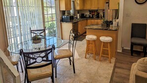 Una cocina moderna con una mesa de comedor de cristal, taburetes de madera y una isla integrada.
