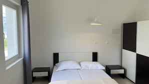 Une chambre moderne avec un lit, des tables de chevet, une armoire et une fenêtre avec des rideaux.