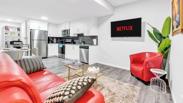 Un salon moderne avec un canapé rouge, une table basse et une cuisine en arrière-plan.