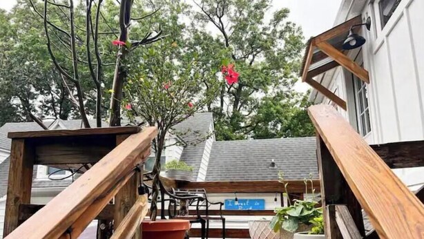 Eine Holzterrasse mit Metallgeländer, einem Blumentopf und einer Bank.