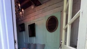 Una habitación acogedora con suelo de madera, una puerta verde y un banco con cojines de colores.
