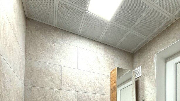 Une salle de bain comprenant des toilettes, un lavabo, un miroir et un meuble de rangement.