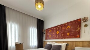 Une chambre à coucher comprenant un lit, une table de chevet, une lampe, un élément de décoration murale et un réfrigérateur.