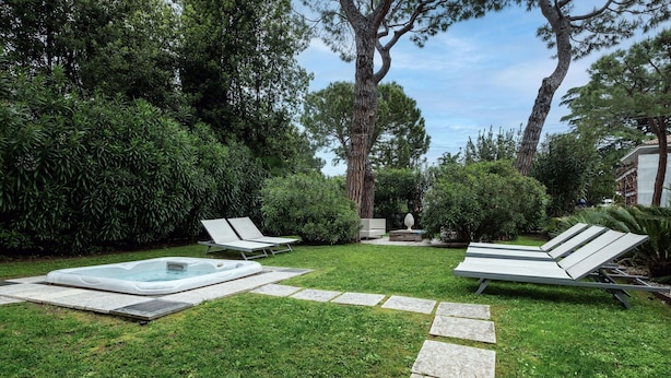 A backyard with a hot tub, two lounge chairs, and a stone pathway. - Dal Molin Apartment, Lago di Garda, Jacuzzi (Desenzano Del Garda)