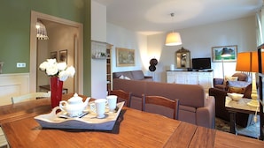 A living room with a dining table set for tea, a sofa, and a television. - Dal Molin Apartment, Lago di Garda, Jacuzzi (Desenzano Del Garda)