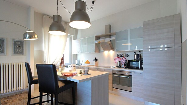 A modern kitchen with a central island, stainless steel appliances, and pendant lighting. - Catullo 18 Apartment, Lago di Garda, Jacuzzi (Desenzano Del Garda)