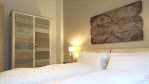 A bedroom with two beds, a wooden wardrobe, a wall-mounted map, and a bedside lamp. - Catullo 18 Apartment, Lago di Garda, Jacuzzi (Desenzano Del Garda)
