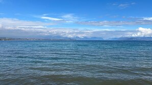 A calm sea with a clear sky and distant mountains. - Catullo 18 Apartment, Lago di Garda, Jacuzzi (Desenzano Del Garda)