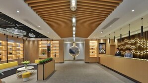 A modern hotel lobby with a wooden ceiling, a reception desk, seating area, and decorative lighting. - Orange Hotel (Suzhou University East Ring Road Subway Station) (Suzhou)