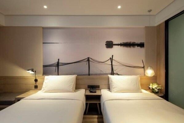 A hotel room with two beds, a nightstand between them, a wall-mounted artwork, and a window with a view. - Orange Hotel (Suzhou University East Ring Road Subway Station) (Suzhou)