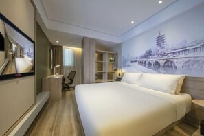 A hotel room with a large bed, a desk, a chair, a wardrobe, and a wall with a mural. - Orange Hotel (Suzhou University East Ring Road Subway Station) (Suzhou)
