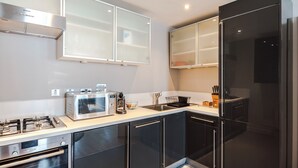 A modern kitchen with stainless steel appliances, black cabinets, and a white countertop. - Immaculate 2-bed Apartment in Prime Central London (London)