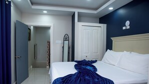 Una habitación de hotel con cama, puerta, espejo y un reloj de pared.