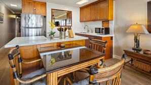 A modern kitchen with wooden cabinets, a stainless steel refrigerator, a glass dining table, and a microwave. - Private Beachfront Retreat in Haleiwa (Haleiwa)