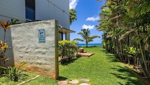 A pathway leading to a building with a sign indicating premises under video surveillance. - Private Beachfront Retreat in Haleiwa (Haleiwa)