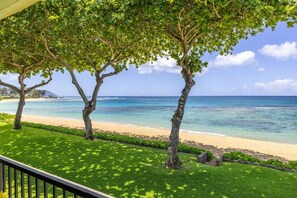 A beachfront property with a well-maintained lawn, a wooden deck, and a view of the ocean. - Private Beachfront Retreat in Haleiwa (Haleiwa)