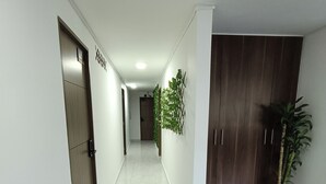 A hallway with a wooden door labeled "MOTEL," a bench, and a potted plant. - AC - House Laureles - Self Checking (Medellín)