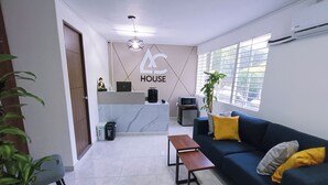 A modern living room with a sofa, a coffee table, and a reception desk. - AC - House Laureles - Self Checking (Medellín)