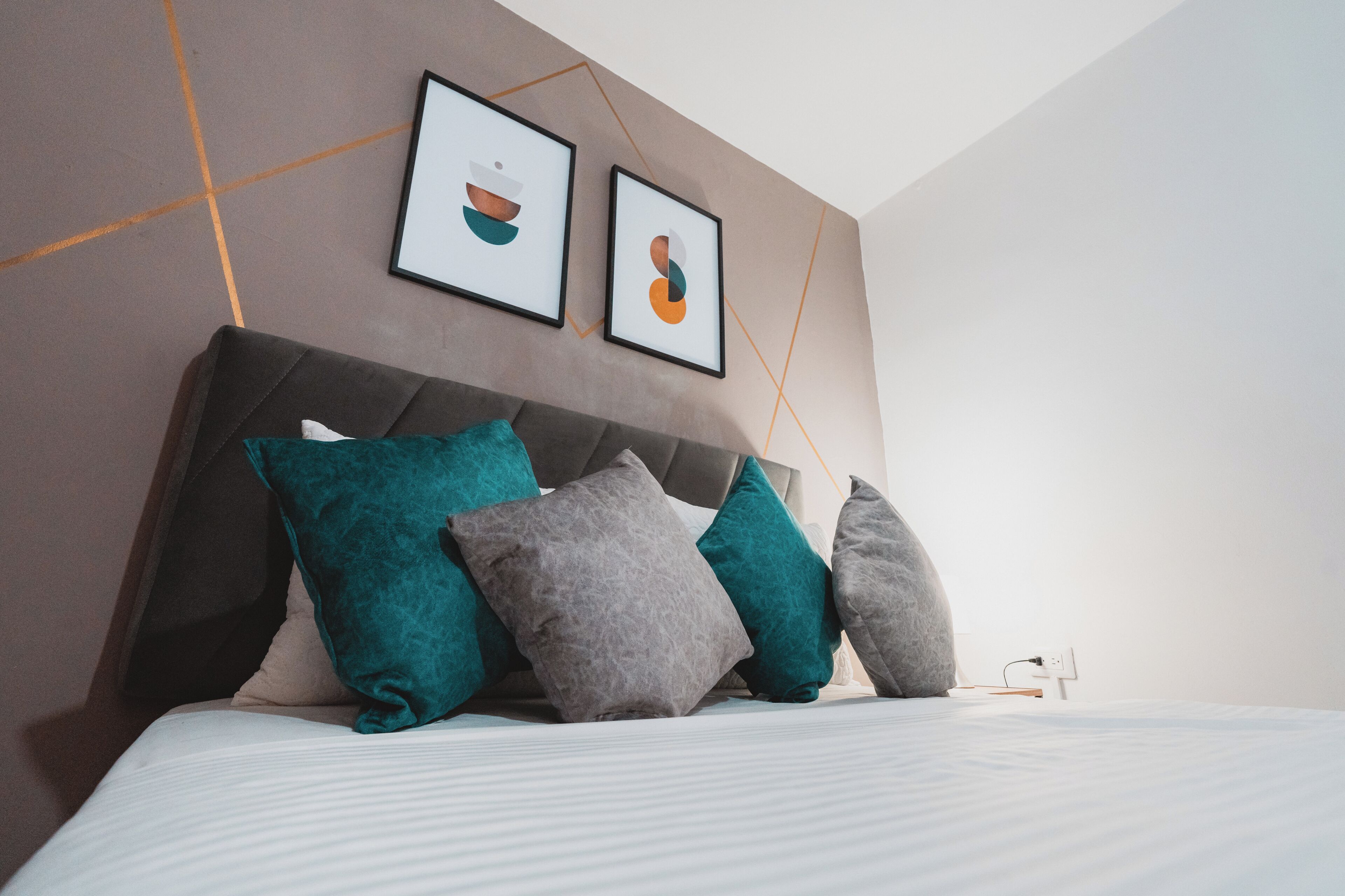 A modern bedroom with a large bed, multiple pillows, and abstract wall art.