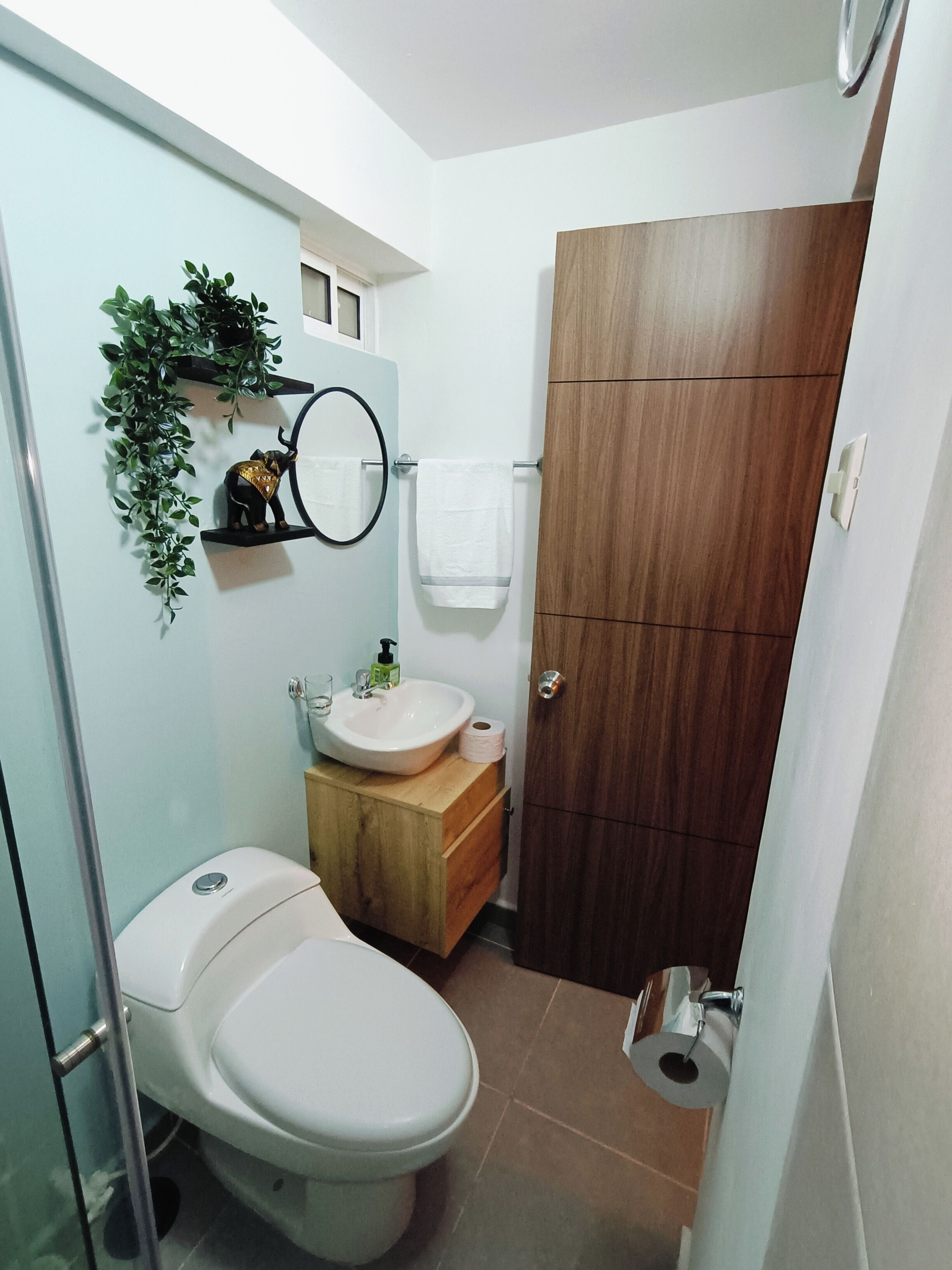 A compact bathroom with a toilet, sink, and wooden cabinet.