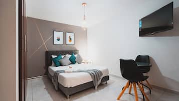 Un dormitorio moderno con una cama, una mesita de noche y un televisor montado en la pared.