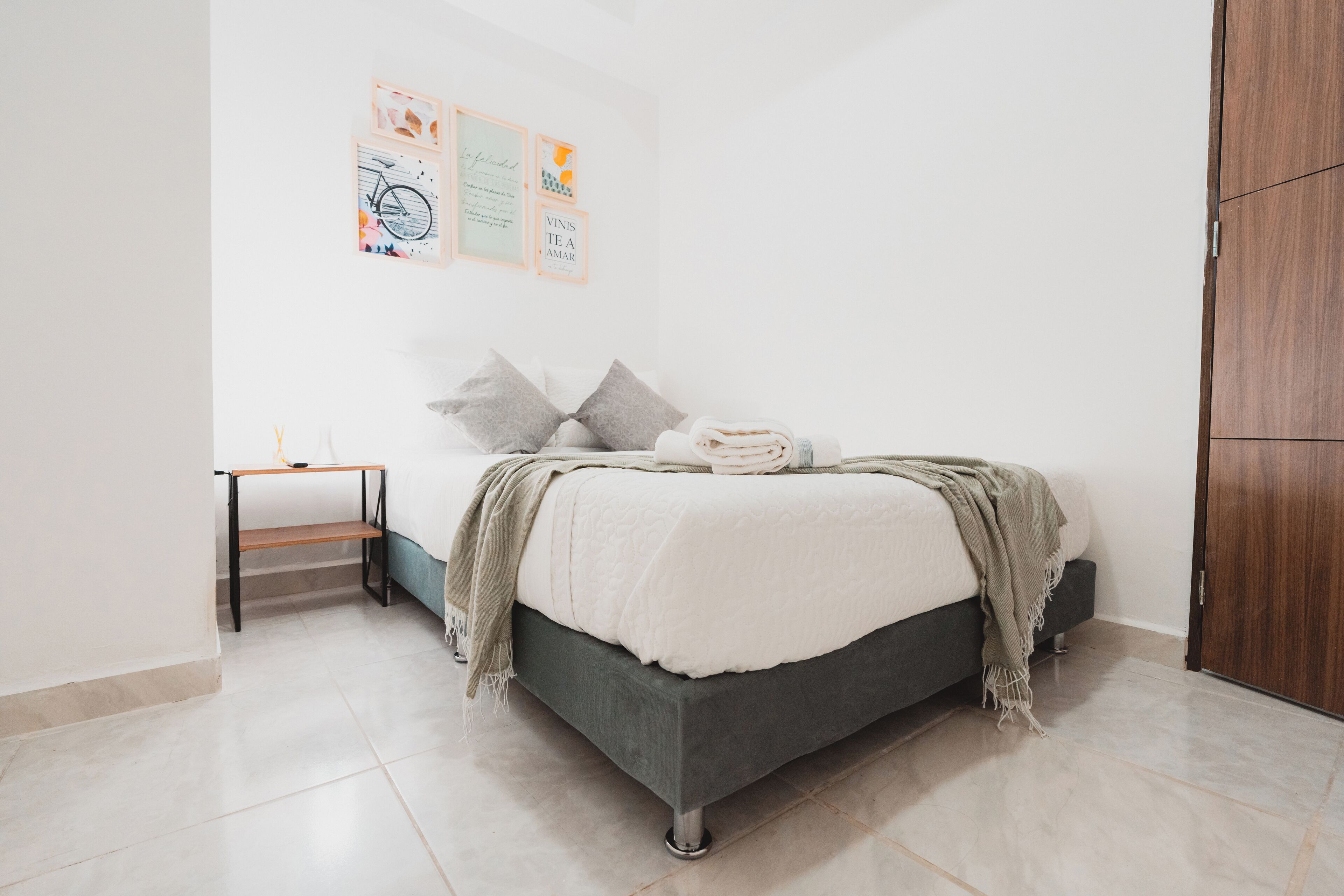 Une chambre à coucher avec un lit, une table de chevet, une étagère et une armoire.