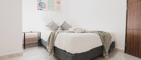 Un dormitorio con cama, mesita de noche, estante y armario.
