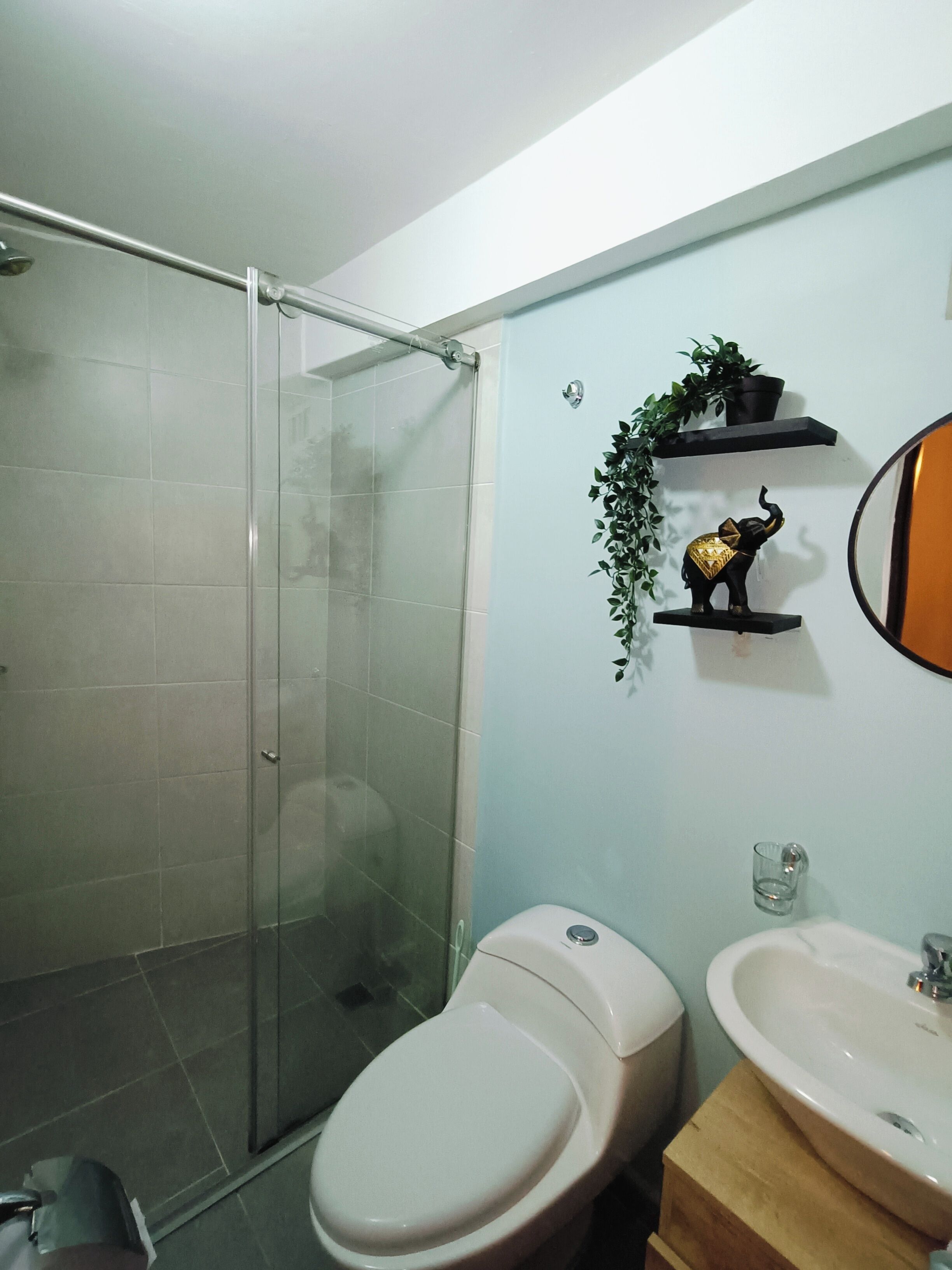 Ein Badezimmer mit Duschkabine, Toilette, Waschbecken und Spiegel.
