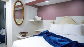 Une chambre d’hôtel comprenant un lit, une table de chevet, un miroir et une étagère décorative.