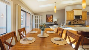 A modern kitchen with a dining area, featuring a wooden table, chairs, and a hanging light fixture. - Oak Creek Oasis: Pool, Views, Golf, Playground (Sedona)