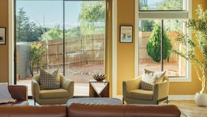 A living room with two armchairs, a sofa, and a large sliding glass door leading to a backyard. - Oak Creek Oasis: Pool, Views, Golf, Playground (Sedona)