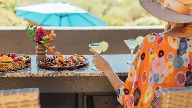 A person seated at an outdoor table with a drink, a plate of food, and a decorative vase with flowers. - Oak Creek Oasis: Pool, Views, Golf, Playground (Sedona)
