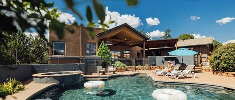 A clear swimming pool with lounge chairs and a hot tub.