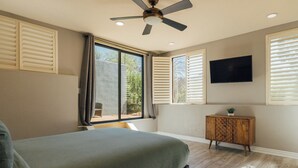 A bedroom with a bed, a ceiling fan, a window with blinds, a television on the wall, and a wooden cabinet. - Oak Creek Oasis: Pool, Views, Golf, Playground (Sedona)