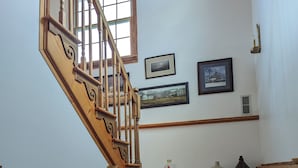 A wooden staircase with a handrail, a window, and two framed pictures on the wall. - Private, light filled retreat space...
     with your own pickleball court! (Berkeley Springs)