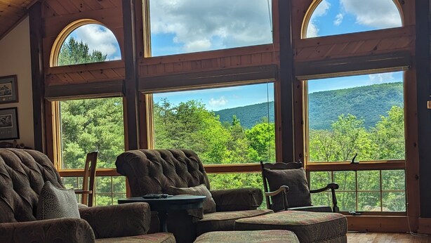 A spacious room with a high ceiling and large windows offering views of a forested mountain. - Private, light filled retreat space...
     with your own pickleball court! (Berkeley Springs)