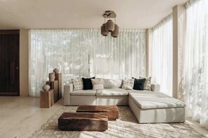 A modern living room with a sectional sofa, a wooden coffee table, and a decorative light fixture.